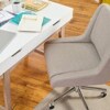 White desk with office supplies and a beige chair with wheels.