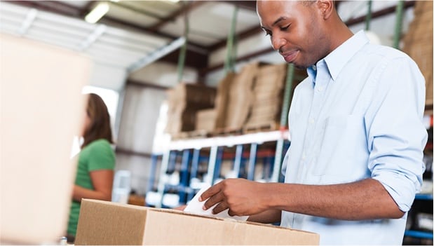 A young man peeling a label off of a package.